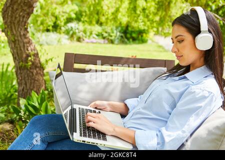 Young freelancer woman having video chat on laptop PC in the garden as a home office Stock Photo