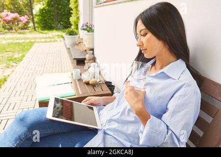 Young business woman as a freelancer using tablet computer at home on the terrace Stock Photo