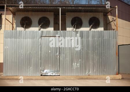 Air conditioners are protected by a grill. Cooling system of the enterprise. Large air filters are enclosed by a metal fence. The backyard of the stor Stock Photo