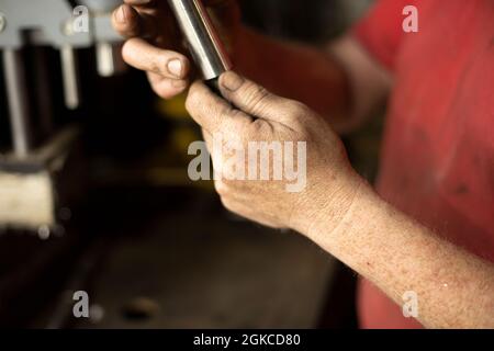 A man pulls out a drill. Installing a drill for a drill. Works in the garage. The master's hands hold the part of the electrical equipment for drillin Stock Photo