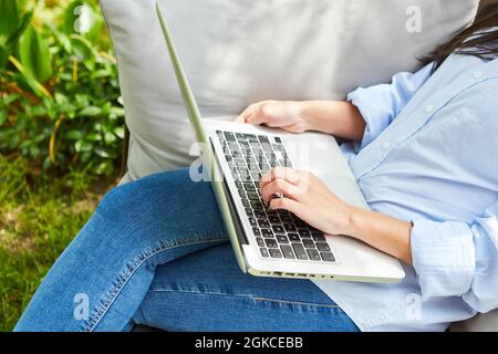 Business woman as freelancer or programmer working on laptop pc in the garden Stock Photo