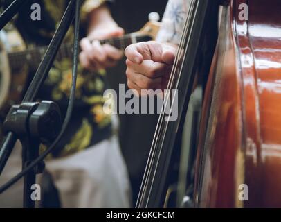 a closeup of a member of a bands hand playing a double bass Stock Photo