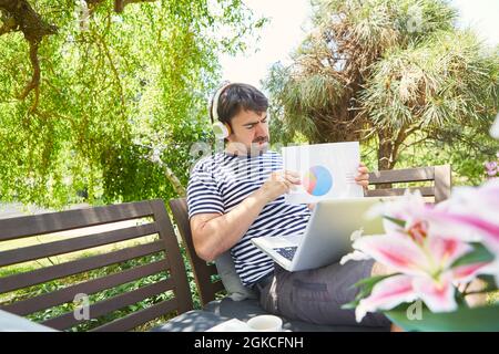 Freelancer with diagram during video conference on the computer in the garden as a home office Stock Photo