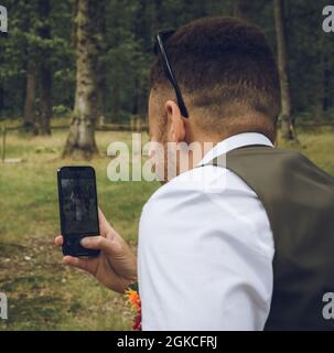 a smartly dressed mixed race man taking a photo with his mobile phone or cell phone Stock Photo