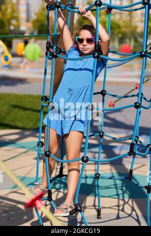 child girl having fun on playground in sunny day Stock Photo