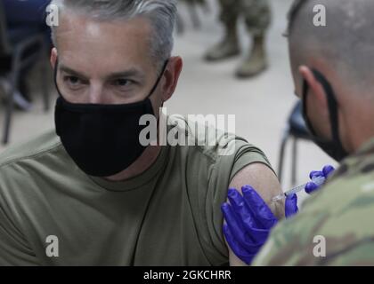 Army Col. John J. Herrman, the commander of Area Support Group-Kuwait, looks away as he receives his Janssen Biotech COVID-19 vaccine at the March 13, 2021 rollout of Operation Med Spear at Camp Arifjan, Kuwait. 'It is one of our highest priorities here at ASG-Kuwait,' Herrman said. 'Without the vaccine, all we're going to do is continue to go up and down in terms of COVID-19 spikes.' Stock Photo