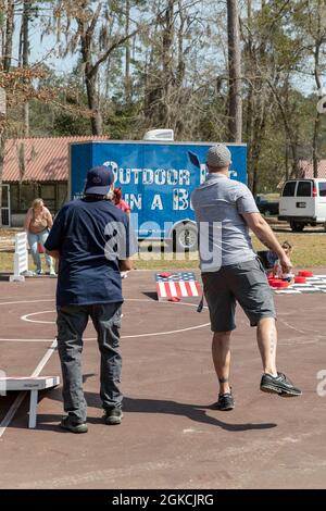 Two attendees play cornhole during Fort Stewart’s Directorate of Family, Morale, Welfare and Recreation’s Outdoor Recreation Department’s second open house, March 13, 2021, at Holbrook Pond in Fort Stewart, Georgia. FMWR celebrated their 50th anniversary of providing outdoor recreational services. Stock Photo