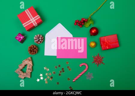 Composition of envelopes with christmas decorations and baubles on green background Stock Photo