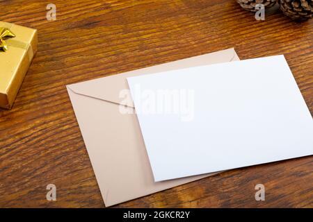 Composition of white card with copy space, envelope and pine cones on wooden background Stock Photo