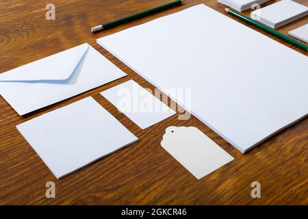 Composition of white cards and envelopes with pencils on wooden background Stock Photo