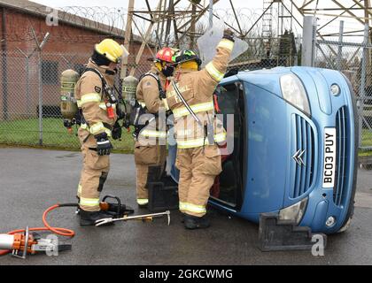Firefighters from the 100th Civil Engineer Squadron Fire Department finish chocking a car and prepare to remove the windshield from an overturned car during a gate runner scenario as part of an exercise at Royal Air Force Mildenhall, England, March 16, 2021. The exercise was made up of a variety of scenarios to test the base’s emergency response and base defense for potential threats. Stock Photo