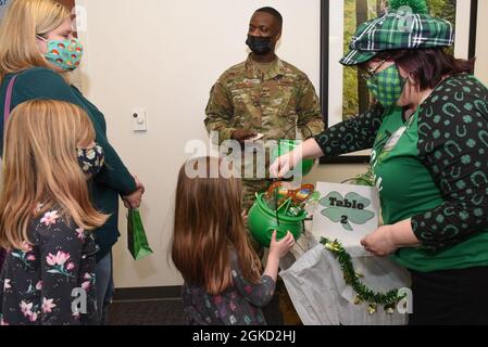 Sharon Noones, right, Exceptional Family Member Program family support coordinator, hands a St. Patrick’s Day-themed gift to Astraea Davies during a Hearts Apart event at Hanscom Air Force Base, Mass., March 17, while Master Sgt. Samuel Burke, a readiness NCO for the Airman and Family Readiness Center, and her mother, Paula, looks on. The Hearts Apart Program offers activities and support to families while a parent or guardian is serving away from home. Stock Photo
