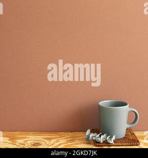 Gray mug cup with eucalyptus leaf on wooden table. brown wall background. copy space Stock Photo