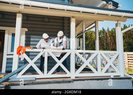 Two male workers on porch inspecting technical document Stock Photo