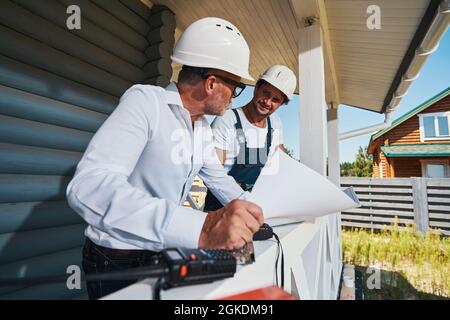 Worker and engineer looking at each other while reading drawings Stock Photo
