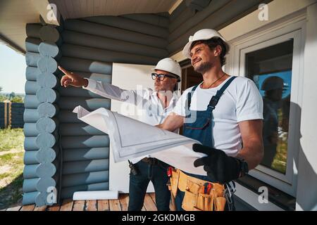 Housebuilder demonstrating something outside to pleased worker Stock Photo