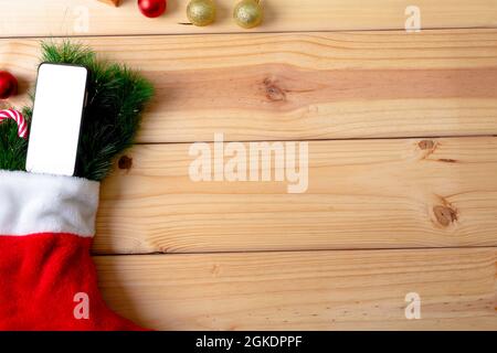 Composition of christmas stocking with fir tree, smartphone and copy space on wooden background Stock Photo