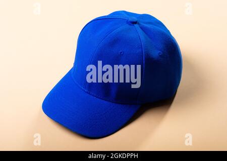 Composition of traditional peaked blue baseball cap on pale brown background Stock Photo