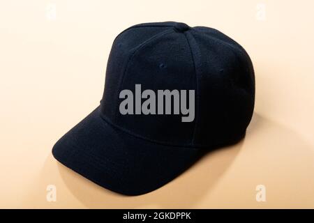 Composition of traditional peaked black baseball cap on pale brown background Stock Photo