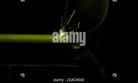 Work of the machine for laser cutting of metal details. HDR. Industrial background with a laser cutting holes in a metal tube on black background Stock Photo
