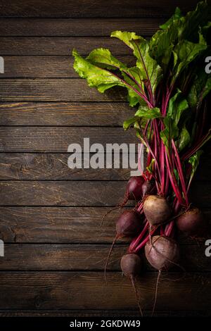 Fresh red beetroot with herbage green leaves over wooden background, top view Stock Photo