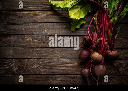 Fresh red beetroot with herbage green leaves over wooden background, top view Stock Photo