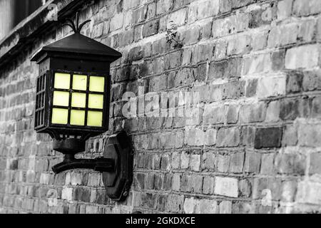 Old steel electric lantern attached to red brick wall Stock Photo