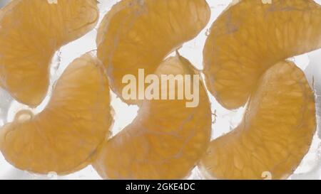 Concept of healthy diet and vitamins. Stock footage. Close up bottom view of peeled tangerine slices lying on glass transparent surface that is being Stock Photo