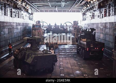 PACIFIC OCEAN (March 26, 2021) U.S. Sailors assigned to the San Antonio-class amphibious transport dock USS Portland (LPD 27), assist with the loading of Marines and equipment from Light Armored Reconnaissance Company, Battalion Landing Team 1/1, 11th Marine Expeditionary Unit, onto a Landing Craft, Air Cushion in the ship’s well deck. U.S. Navy and Marine Corps integration training provides the Essex Amphibious Ready Group/11th MEU its first opportunity to plan, brief, and execute multiple mission packages. The Essex ARG is underway conducting routine operations in U.S. Third Fleet. Stock Photo