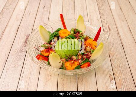 Great and attractive vegetarian salad of avocado, tofu, carrots, peppers, in a transparent glass bowl on a white table Stock Photo