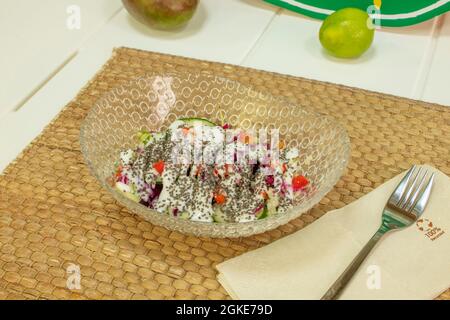 mixed vegetable salad and yogurt drizzled with chia seeds on recycled paper napkin Stock Photo