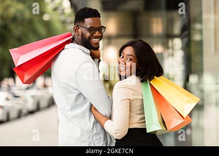 Portrait of happy black couple looking back with shopping bags Stock Photo