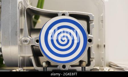 Rotating blue spiral on white background. HDR. Close up of automated mechanism with rotating hypnotic spiral, concept of hypnosis and psychotherapy Stock Photo