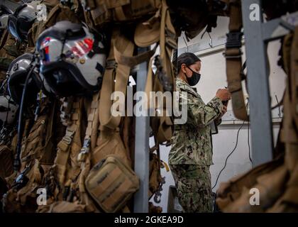 210329-N-PH222-1024 NAVAL AIR STATION FALLON, Nev. (Mar. 29,2021)        Aircrew Survival Equipmentman 2nd Class Vanessa Thomas, from San Diego, assigned to the “Black Knights” of Helicopter Sea Combat (HSC) Squadron 4, inspects aircrew survival gear in the aircrew survival equipmentman shop at Naval Air Station (NAS) Fallon. Air Wing Fallon is part of the predeployment training cycle for Navy's carrier air wings.  HSC-4, along with VFA-2, VFA-192, VFA-113, VFA-147, VAQ-136, VAW-113, and HSM-78 comprise CVW-2 and are detached to NAS Fallon in order to sharpen their warfighting readiness throug Stock Photo