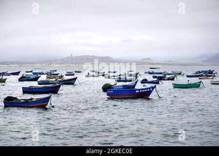 El Dorado, Peru - July 30, 2021: Small moored fishing boats with beach and mountains in background Stock Photo