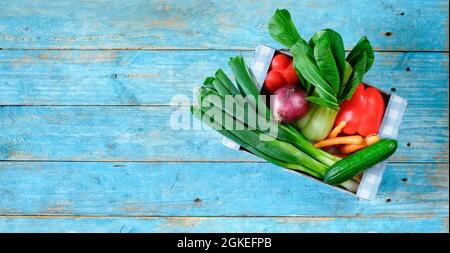 box with various vegetables, healthy eating, dieting concept, flat lay on blue wooden table Stock Photo