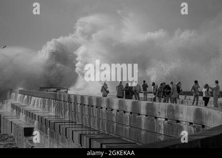 Porto, Portugal - December 31, 2015: People looking at the big stormy waves splashes. River Douro mouth, Porto, Portugal. Stock Photo