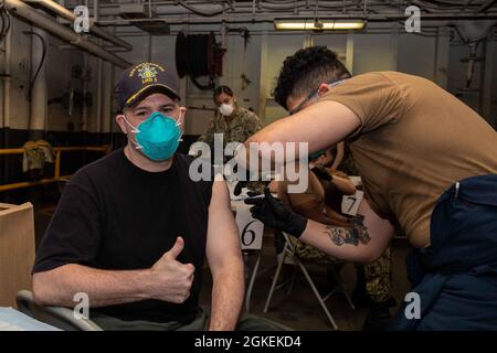 210331-N-EG940-1023 NORFOLK (March 31, 2021) Hospital Corpsman 3rd Class Randy Jimenez administers a Covid-19 vaccine to Capt. Tom Foster, executive officer of the Wasp-class amphibious assault ship USS Kearsarge (LHD 3) March 31, 2021. The Kearsarge medical team, assisted by Fleet Surgical Team 2, 4, and 8, processed over 900 Sailors and Marines through Covid-19 vaccination stations. Stock Photo