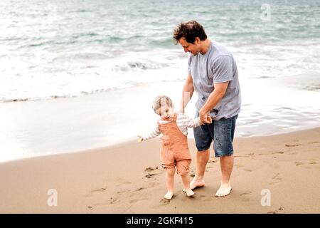 three-year-old boy trying to convince his father that he wants to bathe in the sea Stock Photo