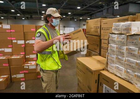 John Sandberg, a volunteer worker with AmeriCorps National Civilian Community Corps, loads supplies in a warehouse at the Fair Park Community Vaccination Center in Dallas, April 7, 2021. Sandberg, a New Haven, Connecticut, native, worked with the Federal Emergency management Agency (FEMA) and Department of Defense organizations to assist with logistics at the CVC. U.S. Northern Command, through U.S. Army North, remains committed to providing continued, flexible Department of Defense support to the Federal Emergency Management Agency as part of the whole-of-government response to COVID-19. Stock Photo