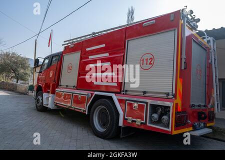 Seferihisar, Izmir, Turkey - 03.09.2021: side view of red traditional fire engine parked in front of local fire department Stock Photo