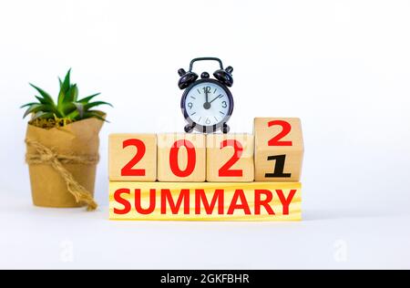 Symbol of planning 2022 summary new year. Alarm clock. Turned a wooden cube, changed words 'summary 2021' to 'summary 2022'. Beautiful white backgroun Stock Photo