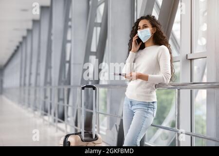 Young Middle Eastern Woman In Medical Mask Talking On Cellphone In Airport Stock Photo
