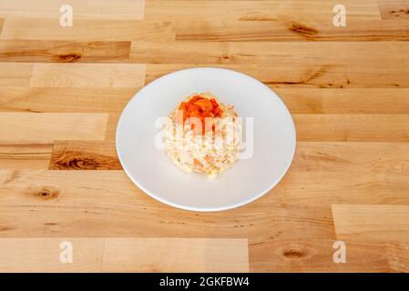Typical Spanish tapa of Russian salad with boiled potatoes, carrots, mayonnaise and roasted red peppers on a white plate Stock Photo
