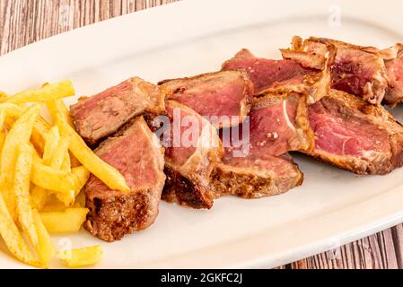Grilled entrecote cooked to the point and cut on a white plate and accompanied by homemade chips Stock Photo
