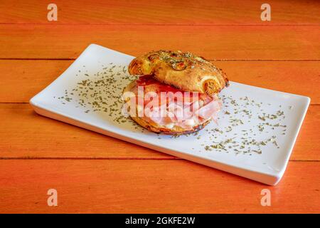 Mixed Italian focaccia with lots of cooked ham, melted cheese, sliced tomato and lots of oregano Stock Photo