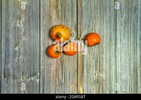 ripe orange persimmons and pomegranate on wooden table Stock Photo