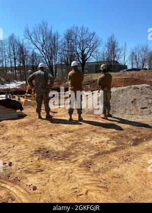 210408-N-N0901-003 SLUNJ, Croatia (Apr. 8, 2021) Utilitiesman Senior Chief Timothy Dry (Det Croatia AOIC), Lieutenant Jordan Shindle (Det Croatia OIC), and Builder Third Class Dane Gunderson (Det Croatia Crew Leader), assigned to Naval Mobile Construction Battalion (NMCB) 11, discuss any issues the crew may be having with placing the formwork after the 8” of snowfall that was received in the area two days before. Stock Photo