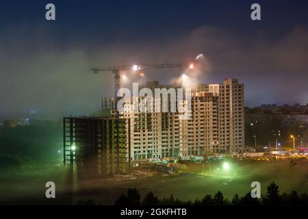 The construction of a multi-storey panel building, building site in the night fog Stock Photo