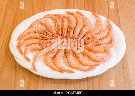 Mediterranean delicatessen tray of prawns to prepare with garlic or grilled on a wooden table. Stock Photo